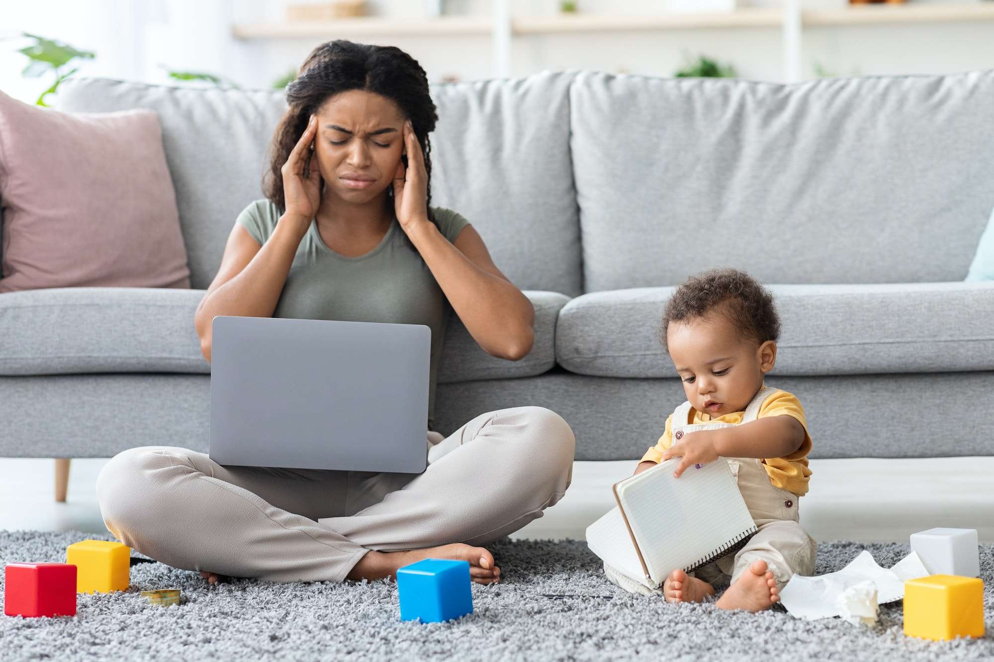 Motherhood Stress. Annoyed Black Mother Working On Computer With Baby At Home